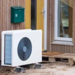 Buitenunit van een warmtepomp in een tuin met geluid dempende omkasting