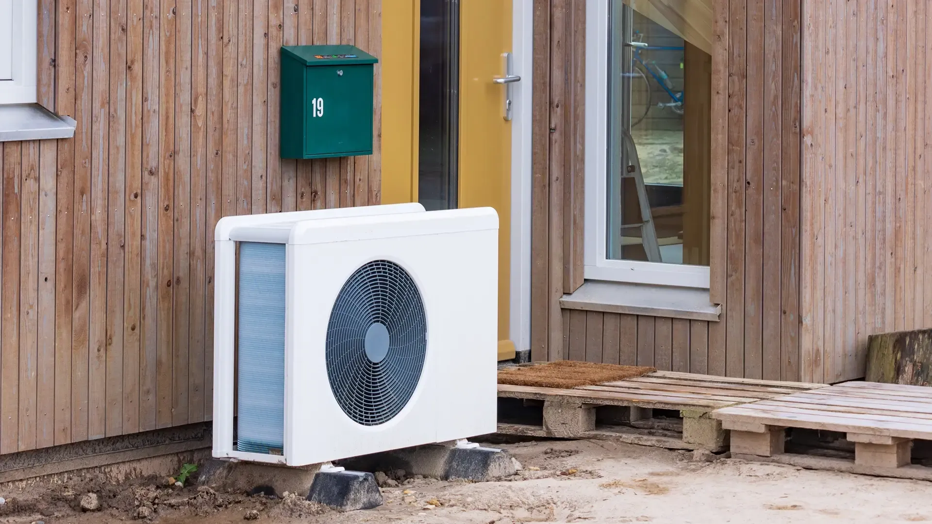 Buitenunit van een warmtepomp in een tuin met geluid dempende omkasting